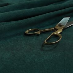 a pair of scissors sitting on top of a green cloth