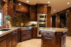 a large kitchen with wooden cabinets and marble counter tops