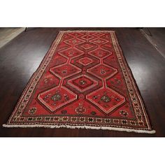 a red rug with an intricate design on the bottom and sides, sitting on a wooden floor