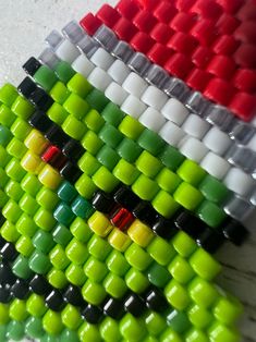 the colorful beads are arranged in rows on the table next to each other and one is red, white, green, yellow, and black