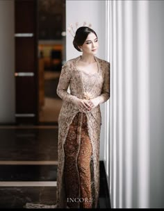 a woman in a dress standing next to a wall