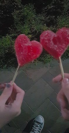 someone holding two heart shaped lollipops in their hands