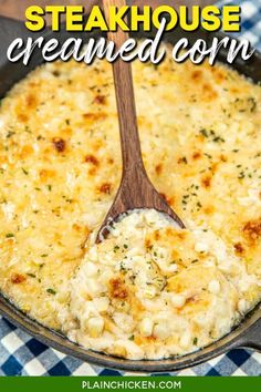 a skillet filled with cheese covered corn and topped with a wooden spoon in it