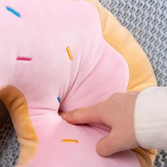 someone is sewing on the back of a pink stuffed animal with sprinkles