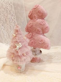 two pink teddy bears sitting next to each other on a white cloth covered tablecloth