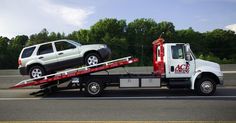 a tow truck hauling a car on the back of it's flatbed trailer