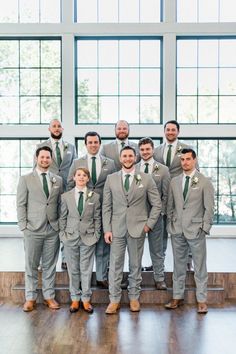 a group of men standing next to each other wearing suits and ties on top of a hard wood floor