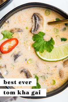 a bowl filled with soup and topped with green garnish next to a slice of lime