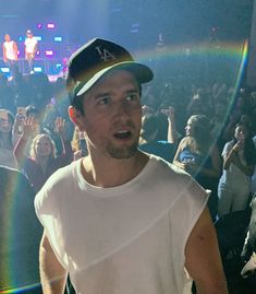 a man standing in front of a crowd at a concert with a rainbow behind him