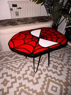 a red and white coffee table sitting on top of a rug next to a plant