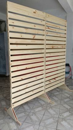 a large wooden screen sitting on top of a tile floor next to a white wall