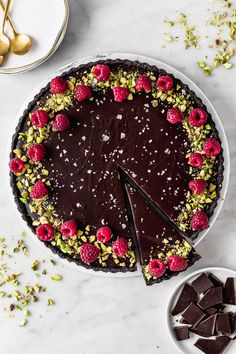 a chocolate tart with raspberries and pistachios on the side