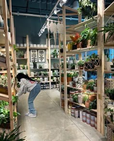 a woman standing in front of shelves filled with plants