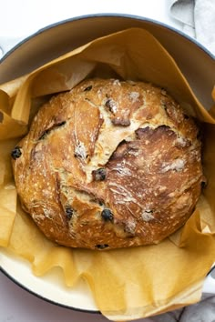 a loaf of bread sitting inside of a pan on top of a white table cloth