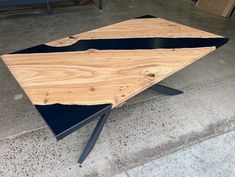 a wooden table with black metal legs on concrete flooring next to cement wall and door