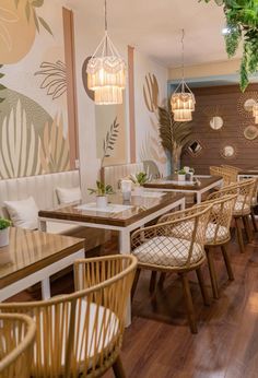 the interior of a restaurant with wooden tables and wicker chairs, potted plants hanging from the ceiling