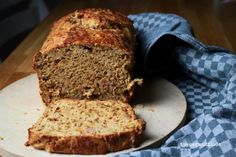 a loaf of banana bread sitting on top of a cutting board next to a blue towel