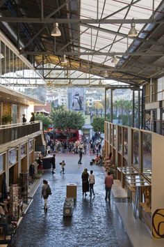 an indoor mall with people walking around and shops on the other side of the walkway