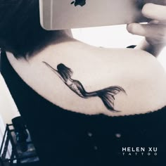 a woman with a tattoo on her back is taking a selfie in the mirror