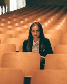 a woman is sitting in the middle of rows of chairs with her hands on her hips