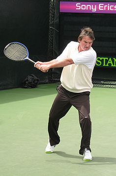 a man swinging a tennis racquet on top of a tennis court at a game