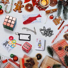 christmas decorations and gifts laid out on a white surface with candy canes, pine cones, candies, candles, etc