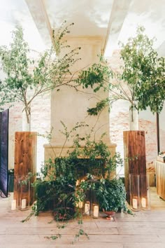 an indoor fireplace with candles and greenery in front of it, surrounded by tall wooden pillars