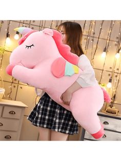 a woman holding a large pink unicorn stuffed animal