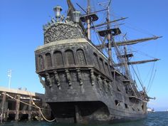 an old pirate ship in the water next to a dock