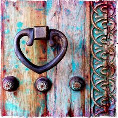 an old wooden door with metal handle and heart shaped knobs on the front side