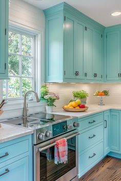 a kitchen with blue cabinets and white counter tops, stainless steel oven and dishwasher