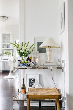 a living room filled with furniture and a lamp on top of a wooden table in front of a white wall