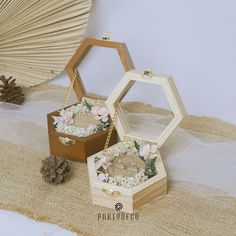 two small wooden boxes with flowers inside on a table next to pine cones and an umbrella