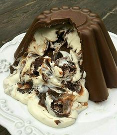 an ice cream sundae on a white plate with chocolate and marshmallows