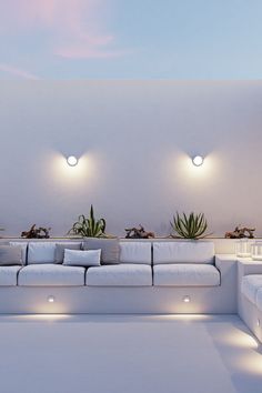 a modern living room with white couches and potted plants