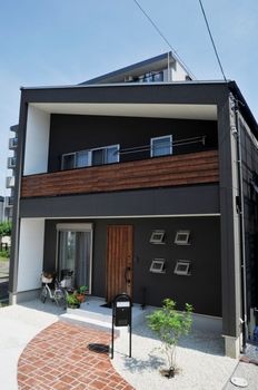 a black and white two story house with brick walkway