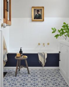 a bathroom with blue and white tile flooring next to a painting on the wall