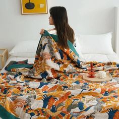 a woman sitting on top of a bed covered in a colorful comforter and blanket