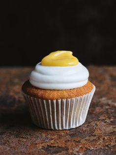 a cupcake with white frosting and a yellow icing on top sitting on a table