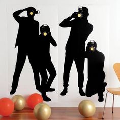 two silhouettes of people with cameras are shown in front of some balloons and balls