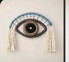 an eye with tassels hanging from it's side on a white wall