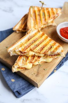 grilled cheese sandwich cut in half on a cutting board with ketchup and mustard