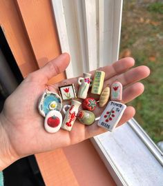 a person is holding many small magnets in their hand near a window sill