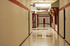 an empty hallway with red and white stripes on the walls, and a clock hanging from the ceiling