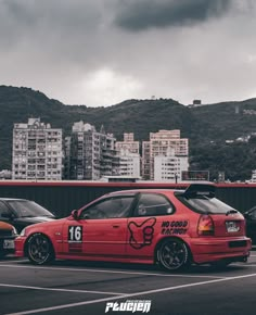 two cars parked in a parking lot next to each other with city buildings in the background