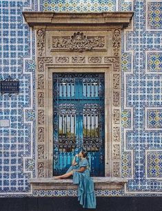 a woman standing in front of a blue and yellow building