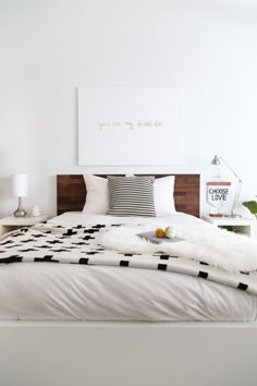 a bed with white sheets and black and white decor on the headboard is shown