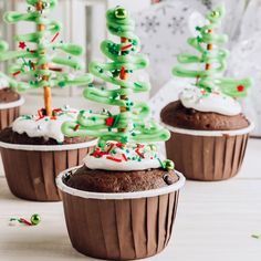 three cupcakes decorated with green icing and sprinkles are sitting on a table