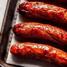 three sausages are lined up on a baking sheet