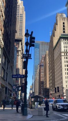 people are walking on the sidewalk in an urban area with tall buildings and traffic lights